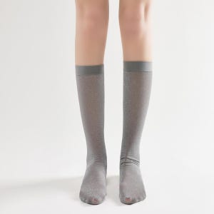 Pu&ograve; includere: Un paio di calze grigie al ginocchio con un leggero luccichio.