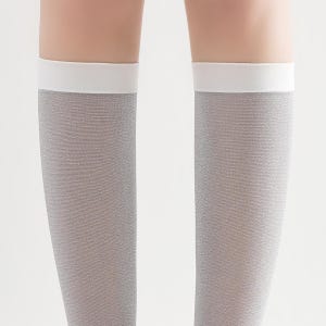 May include: A pair of knee-high socks in a light gray color with a white band at the top. The socks have a subtle shimmer and a textured appearance. The background is plain white.