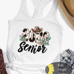 May include: White tank top with a graphic design featuring the text "2024 Senior" in black script. The numbers are decorated with a cowhide pattern and a cowboy hat. Cacti and pink flowers are also included in the design.