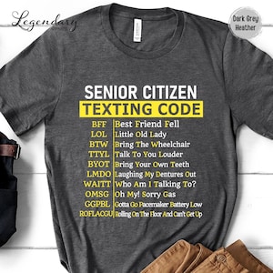May include: Dark grey heather t-shirt with the text "SENIOR CITIZEN TEXTING CODE" in white and yellow. The shirt lists texting acronyms and their meanings, such as "BFF" for "Best Friend Fell" and "LOL" for "Little Old Lady".