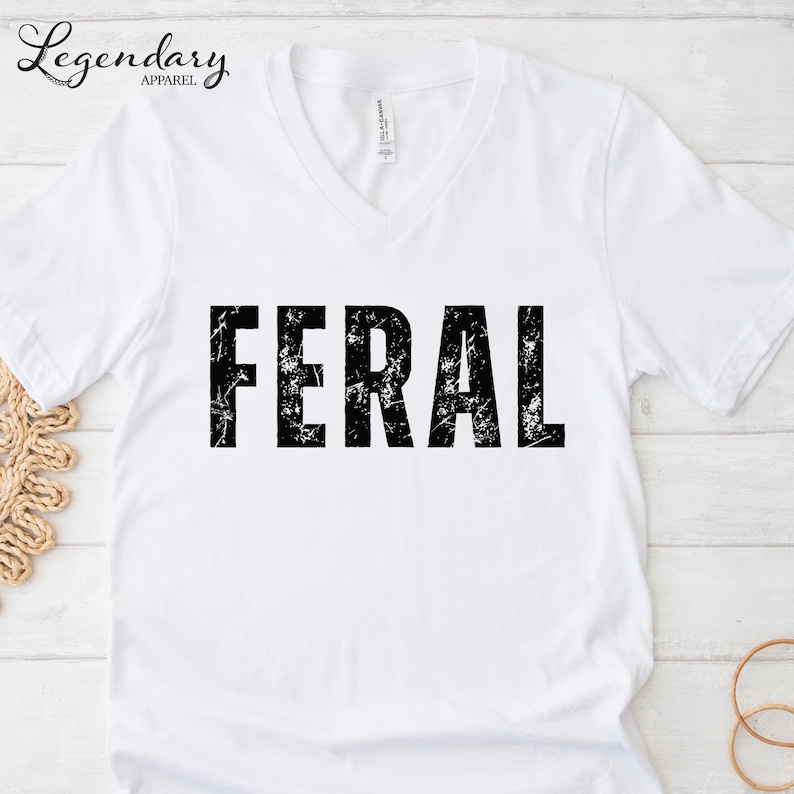 A white t-shirt with the word "FERAL" printed in a distressed, distressed font.