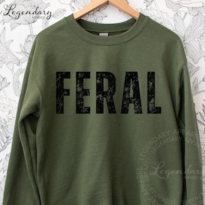 A green sweatshirt with the word "FERAL" printed in large, distressed letters across the front.