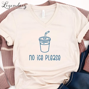 May include: Cream-colored V-neck t-shirt with a blue graphic of a drink cup and straw. The text "no ice PLEASE" is below the graphic. The shirt has the "Legendary Apparel" logo in the upper left corner.