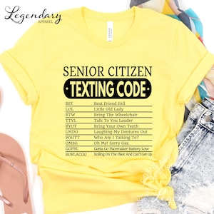 a yellow t-shirt with a list of various texts and phrases, including "Best Friend Fell", "Little Old Lady", "Bring The Wheelchair", "Talk To You", "Bring Your Own Teeth", "Laughing My Dentures Out", "Who Am I Talking To?", "Gonna Go Pecemaker Battery Low", and "Rolling On The Floor And Can't Get Up".