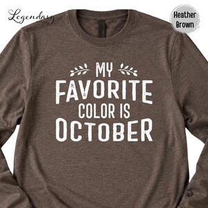 a brown long-sleeved t-shirt with a white text design printed on it. The text reads "My favorite color is October".