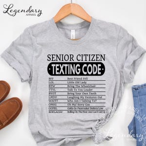 A gray t-shirt with a humorous list of "senior citizen texting code" written in black text.