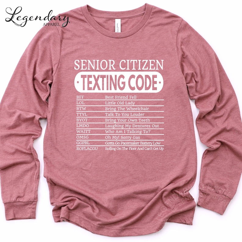 A pink long-sleeved shirt with a humorous text printed on it, which appears to be a list of rules or guidelines for senior citizens when it comes to texting.