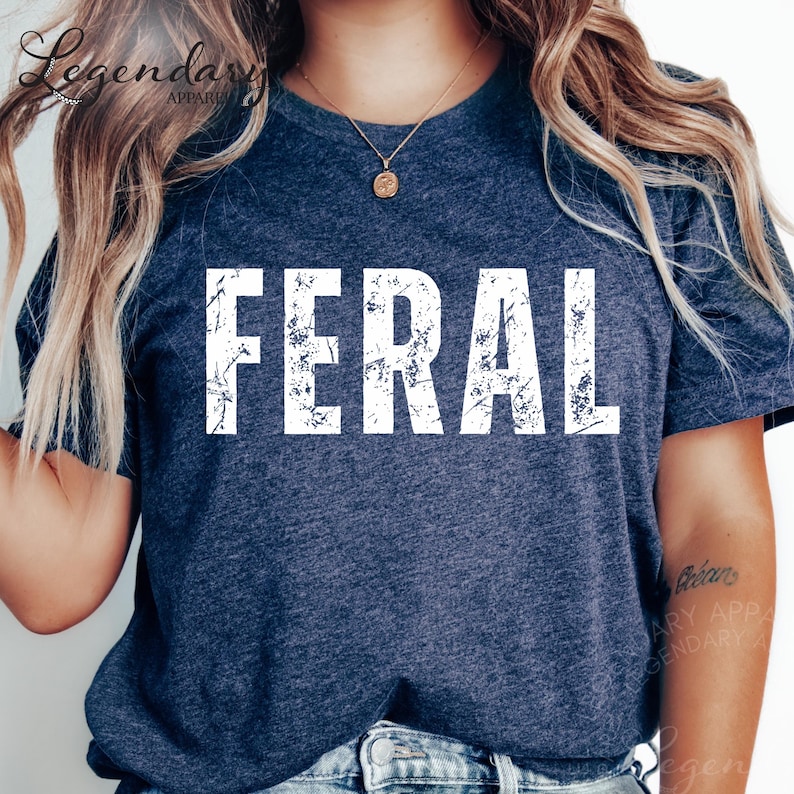 A person wearing a navy blue t-shirt with the word "FERAL" printed on it.