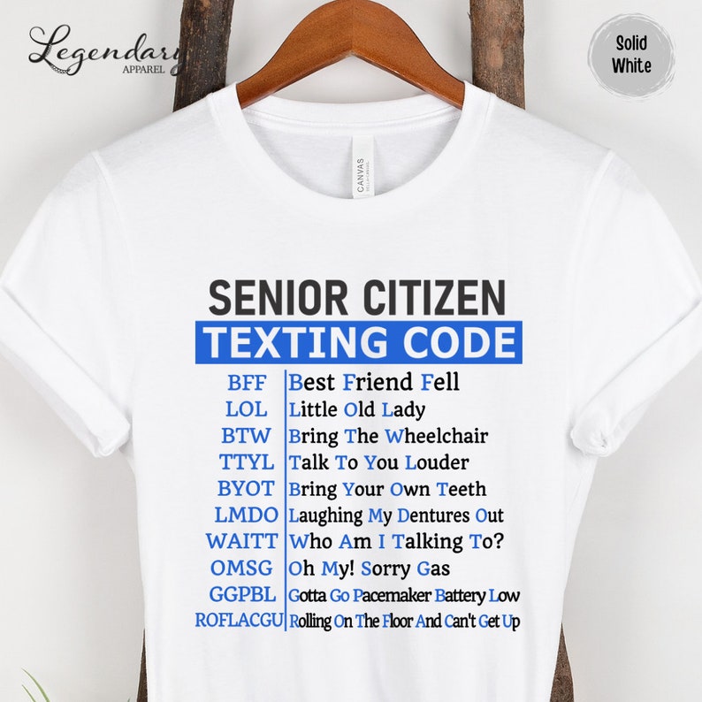 May include: White t-shirt with blue text that reads "Senior Citizen Texting Code" and a list of abbreviations and their meanings. The abbreviations are: BFF, LOL, BTW, TTYL, BYOT, LMDO, WAITT, OMSG, GGPBL, ROFLACGU.