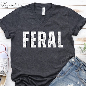 a gray t-shirt with the word "FERAL" printed on it, along with a pair of jeans and a pair of sneakers.