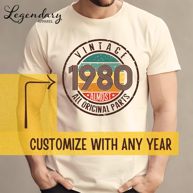 May include: Cream-colored t-shirt with a retro design featuring the year "1980" in a circular emblem. The emblem includes the words "VINTAGE" and "ALL ORIGINAL PARTS". The text "CUSTOMIZE WITH ANY YEAR" is at the bottom.