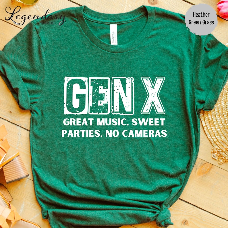 A green t-shirt with white text printed on it, placed on a wooden surface.
