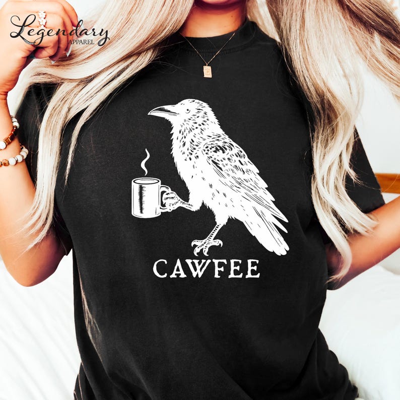 A person wearing a black t-shirt with a white graphic design depicting a bird holding a coffee cup.