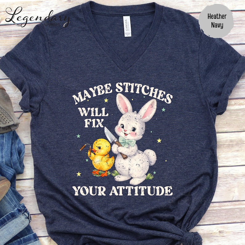 A navy blue t-shirt with a graphic design featuring a rabbit and a duck holding a sign that says "MAYBE STITCHS WILL FIX YOUR ATTITUDE".