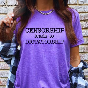 A person wearing a purple t-shirt with the text "CENSORSHIP LEADS TO DICTATORSHIP" printed on it.
