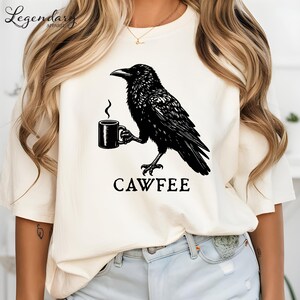 A white t-shirt with a black crow graphic and the text "CAWFEE" printed on it.