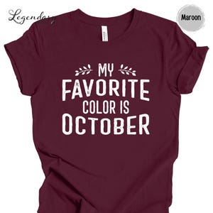 The image is a maroon t-shirt with the text "MY FAVORITE COLOR IS OCTOBER" printed on it.