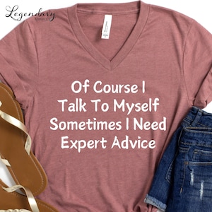 May include: A mauve v-neck t-shirt with the text "Of Course I Talk To Myself Sometimes I Need Expert Advice" printed in white.