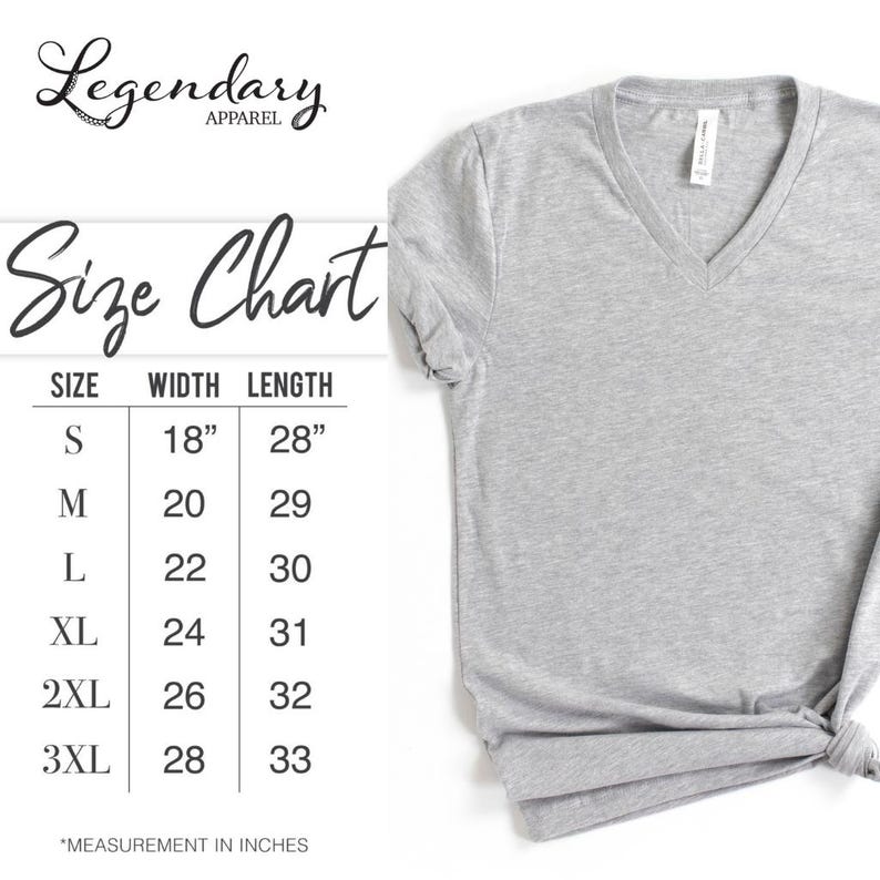 Pode incluir: Uma camiseta cinza claro com decote em V com uma tabela de tamanhos. A tabela de tamanhos mostra as medidas em polegadas para os tamanhos S a 3XL. A camiseta &eacute; da Legendary Apparel.