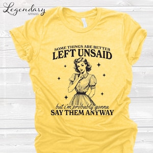 Może przedstawiać: Ż&oacute;łta koszulka z napisem "Some things are better left unsaid" i "but I'm probably gonna say them anyway". Koszulka przedstawia ilustrację w stylu vintage kobiety z palcem na ustach. Logo Legendary Apparel znajduje się w lewym g&oacute;rnym rogu.
