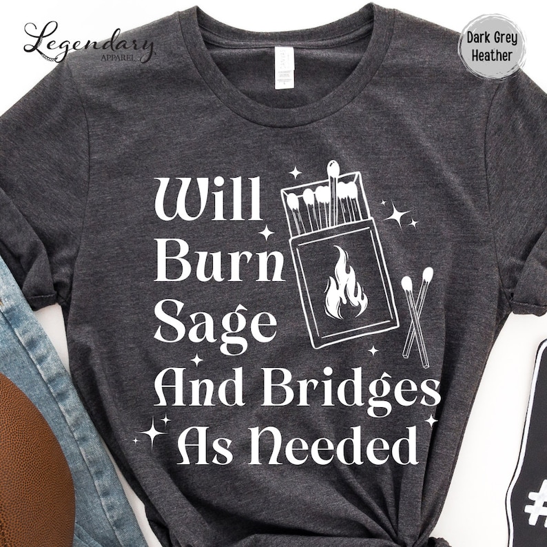 May include: Dark grey heather t-shirt with white text that reads "Will Burn Sage And Bridges As Needed". The text is accompanied by a graphic of a matchbox with matches and a flame.