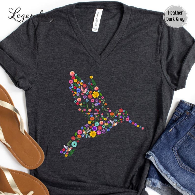 May include: Heather dark grey V-neck t-shirt with a floral hummingbird design. The hummingbird is made up of colorful flowers and leaves.