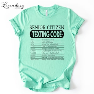 A mint green t-shirt with a humorous text that reads "SENIOR CITIZEN TEXTING CODE" printed on it.