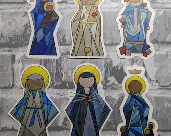 Könnte beinhalten: Sechs Aufkleber mit der Darstellung der Heiligen Maria. Jeder Aufkleber hat ein geometrisches Design mit goldenen Heiligenscheinen und Gewändern in Blau, Grau und Beige. Der Text "Blessed Virgin Mary" befindet sich unten.