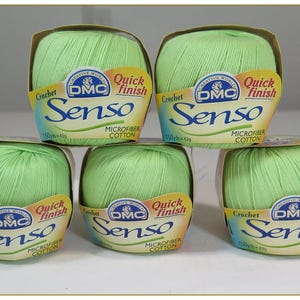 May include: Five spools of light green DMC Senso microfiber cotton yarn for crochet projects. Each spool is labeled with the DMC logo and the words "Quick Finish". The yarn is packaged in a cardboard container.
