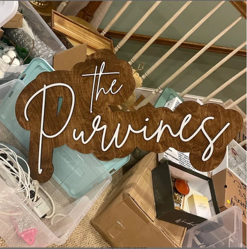 Pode incluir: Uma placa de madeira com as palavras "The Purvines" escritas em letras brancas cursivas. A placa &eacute; marrom e tem um visual envelhecido.
