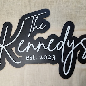 Peut inclure: Une pancarte en bois noir avec une inscription blanche qui dit "The Kennedys est. 2023".