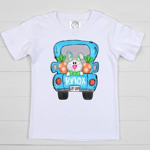 May include: White t-shirt with a blue truck graphic. The truck has a bunny rabbit in the back with carrots. The truck has a license plate that says "KNOX HIP HOP".