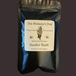 May include: Black pouch with a label that reads "The Monkey's Paw" and "Goofer Dust." The label features a hand illustration, skulls, and the text "Authentic Hoodoo." The bottom of the label reads "Caustic. Do Not Ingest."