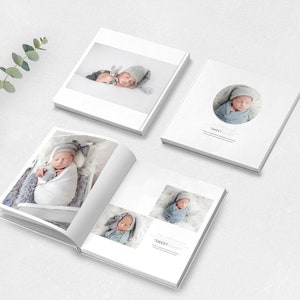 May include: A white photo album with a baby in a white blanket and a gray hat. The album has a circle on the cover with the text "Sweet Dreams" inside.