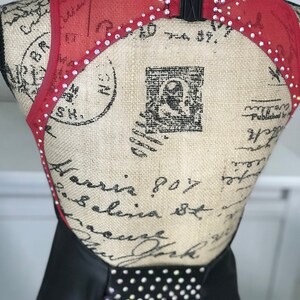 May include: Black and red dance costume with a mesh back and rhinestones. The costume has a halter neckline and a fitted bodice.