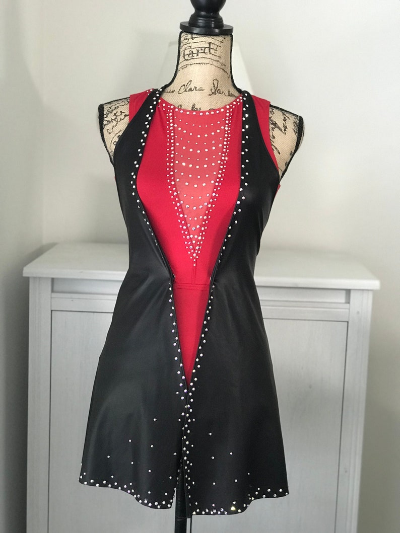 May include: A black sleeveless dress with a red bodice and a sheer mesh panel. The dress is adorned with rhinestones.