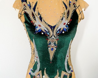 May include: A green velvet leotard with gold, silver, blue and red embellishments. The leotard has a sheer mesh neckline and short sleeves.