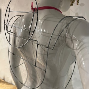 以下が含まれることがあります： コスチューム用の銀色のワイヤーフレーム。翼の形で、中央に円形のフレームがあります。
