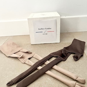 Peut inclure: Deux ensembles de bretelles pour un vêtement, un ensemble est brun et l'autre beige. Les bretelles sont en tissu doux et ont un design simple. Les bretelles sont disposées sur une surface brun clair.