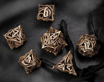 May include: Six intricately designed metal dice with ornate patterns and numbers 4, 6, 12, 20, and 3 on each face. The dice are a dark bronze color and are resting on a dark, textured surface.