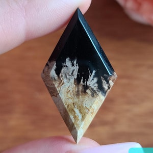 Può includere: Un ciondolo in resina a forma di diamante nero e bianco con un motivo a spirale di bianco e marrone.