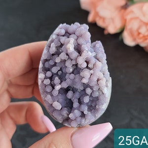 May include: A purple agate geode with a unique, speckled pattern. The geode is smooth and polished, with a natural, organic shape.