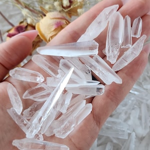 May include: A collection of clear quartz crystal points, also known as rock crystals, in various sizes and shapes. The crystals are arranged in a hand, showcasing their natural beauty and clarity.