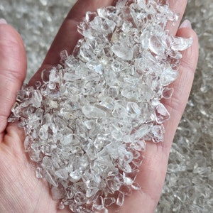 May include: A handful of clear quartz chips, also known as rock crystals, in various sizes and shapes. The chips are translucent and have a natural, unpolished finish.