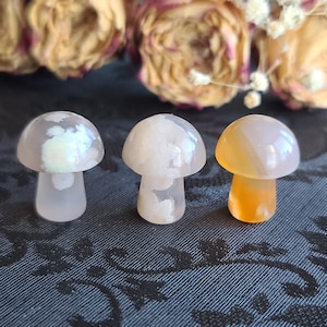 May include: Three agate mushroom shaped stones. One is white, one is white with a iridescent sheen, and one is orange and white.