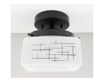 Może przedstawiać: Czarna lampa sufitowa z białym kloszem szklanym z geometrycznym wzorem czarnych linii.