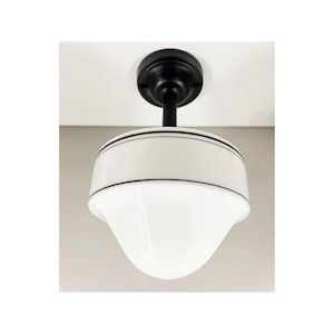 May include: A white porcelain ceiling light fixture with a black metal base and two black bands around the top edge of the shade.