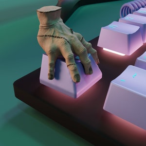 Può includere: Primo piano di una mano con cuciture cucite che preme un tasto viola della tastiera. La tastiera ha una base grigio scuro e altri tasti viola.