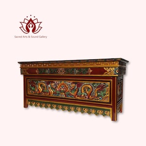 Può includere: Un tavolo da altare in legno rosso con intricate sculture di draghi e fiori in oro e verde. Il tavolo ha un piano superiore piatto e uno scaffale inferiore decorativo.