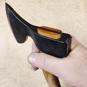 May include: A black handled axe with a wooden handle and a brown and black wood inlay on the top of the handle.